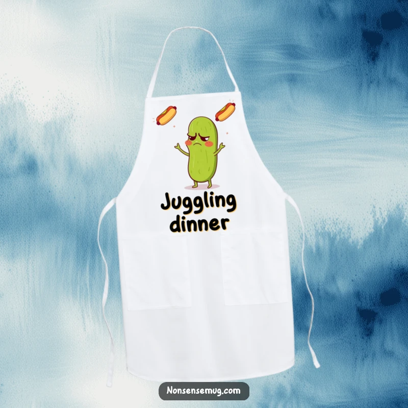 Funny apron depicting a grumpy pickle with a confused expression, juggling three flying hot dogs, for kitchen humor.
