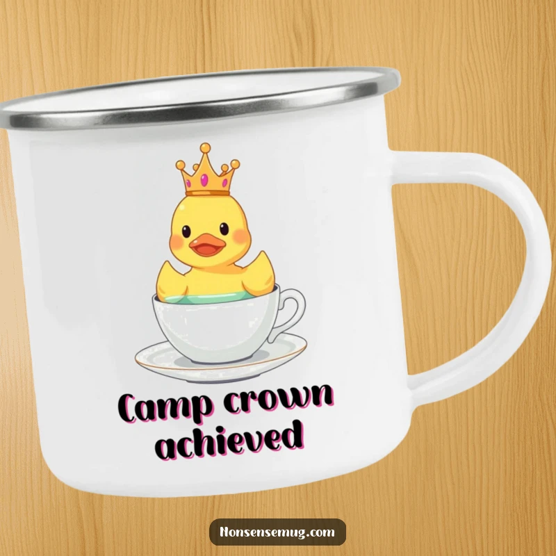 Funny crowned rubber duck floating in a teacup on a humorous camping mug.